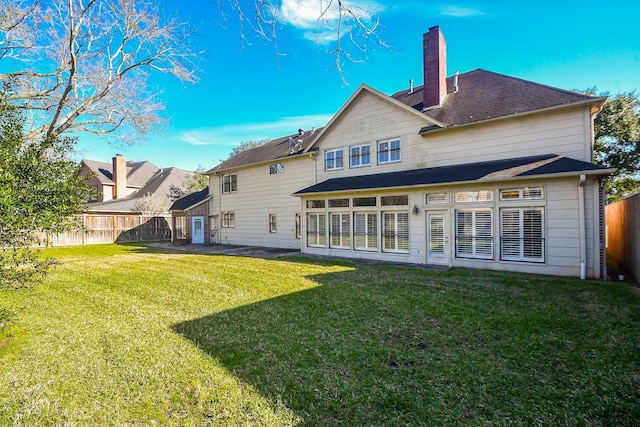 back of house featuring a lawn, a chimney, and a fenced backyard