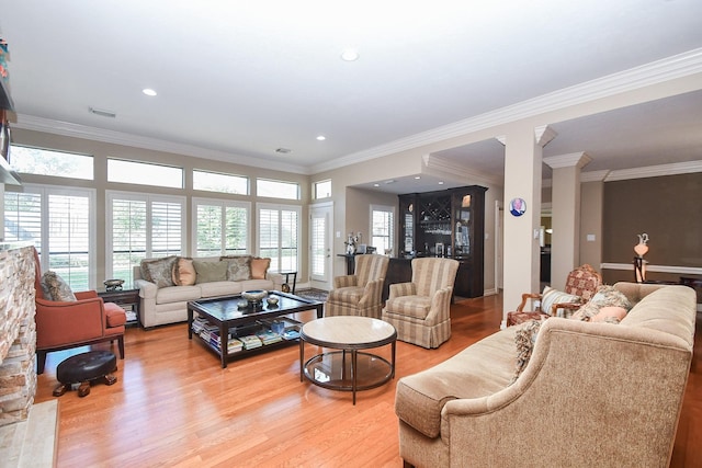 living area featuring light wood-style flooring, a healthy amount of sunlight, visible vents, and ornate columns