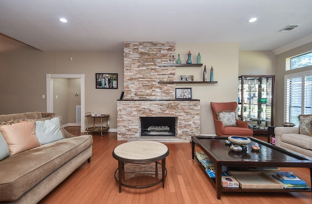 living room featuring visible vents, a stone fireplace, and wood finished floors