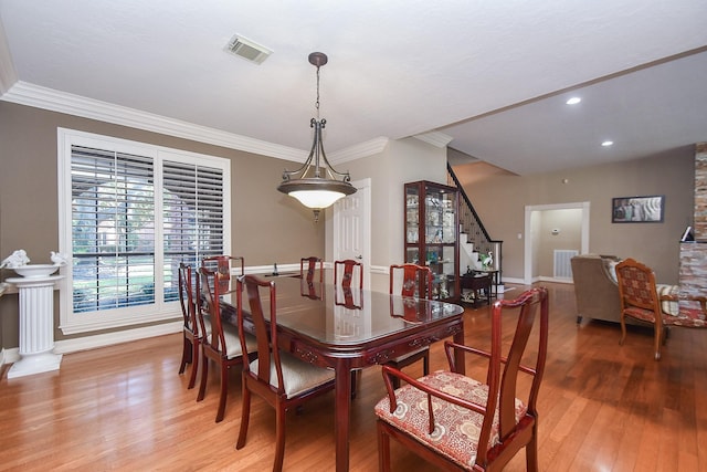 dining area with stairway, ornamental molding, visible vents, and light wood-type flooring