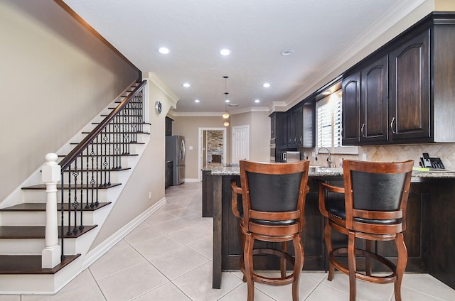 bar with baseboards, light tile patterned flooring, freestanding refrigerator, crown molding, and tasteful backsplash