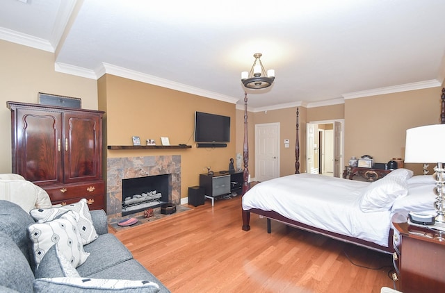 bedroom with crown molding, light wood-type flooring, and a tile fireplace