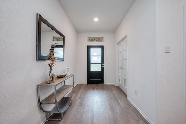 foyer entrance featuring wood finished floors, visible vents, and baseboards