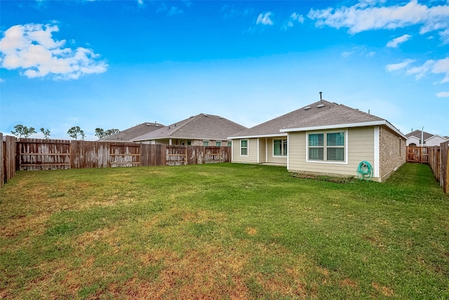 rear view of house featuring a lawn and a fenced backyard