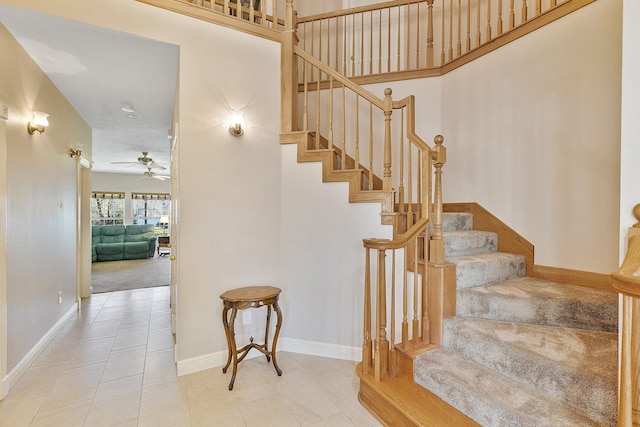 staircase with a ceiling fan, baseboards, and tile patterned floors