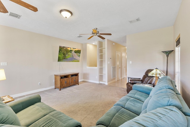 carpeted living room featuring baseboards, visible vents, and a ceiling fan