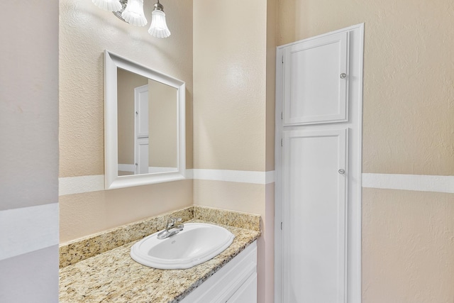 bathroom with a textured wall and vanity