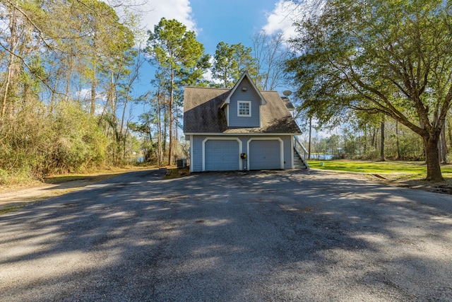 view of property exterior featuring driveway, an attached garage, and roof with shingles