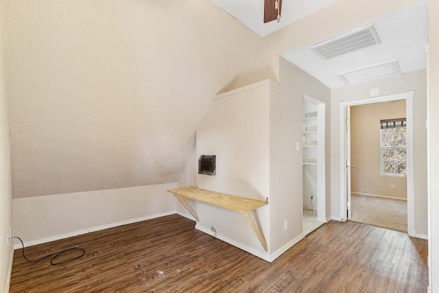 interior space with attic access, visible vents, vaulted ceiling, and wood finished floors