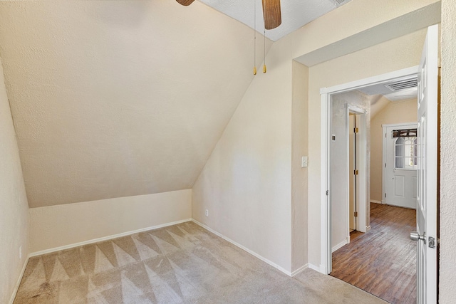 bonus room with lofted ceiling, ceiling fan, light carpet, visible vents, and baseboards