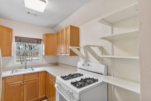 kitchen featuring a sink, visible vents, white range with gas cooktop, light countertops, and open shelves