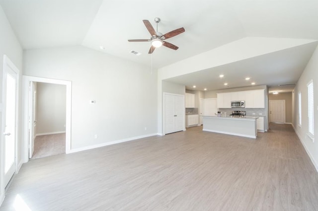 unfurnished living room with plenty of natural light, visible vents, vaulted ceiling, and light wood finished floors