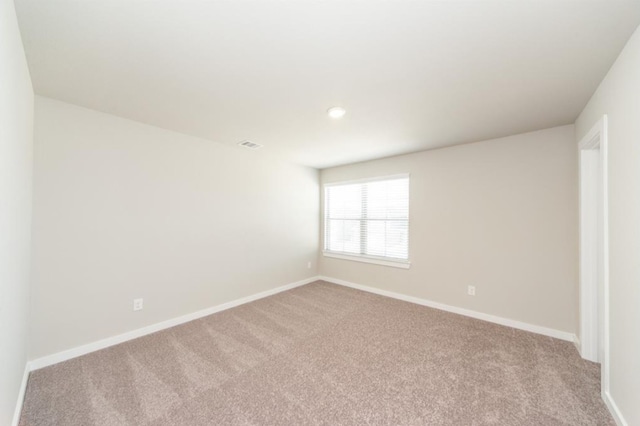 unfurnished room featuring carpet flooring, visible vents, and baseboards