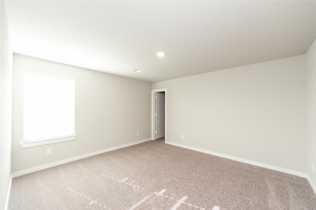 spare room featuring carpet and baseboards