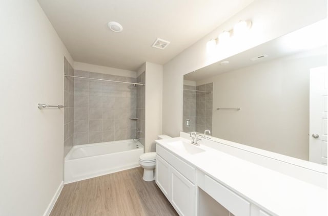 bathroom featuring visible vents, toilet, wood finished floors, vanity, and shower / bathing tub combination