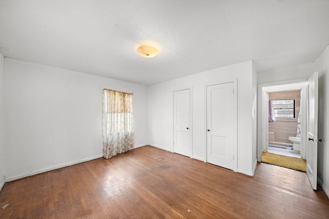 unfurnished bedroom with hardwood / wood-style flooring and baseboards