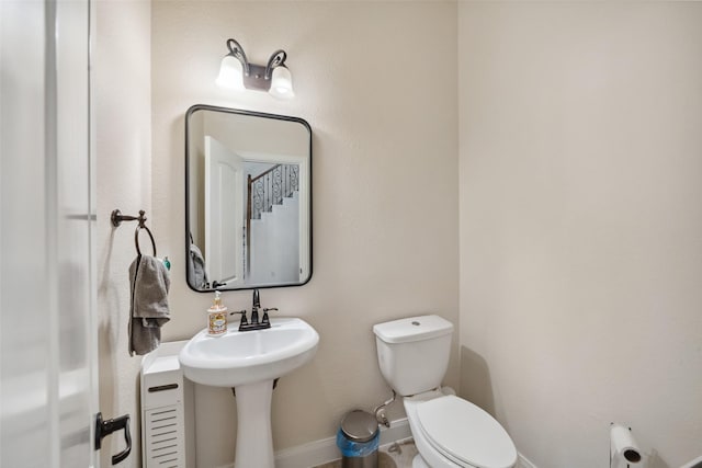 half bathroom with a sink, toilet, and baseboards