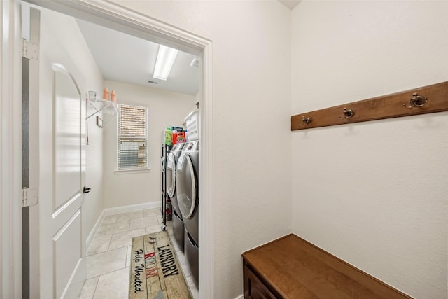 laundry room with laundry area, washing machine and dryer, light tile patterned floors, and baseboards