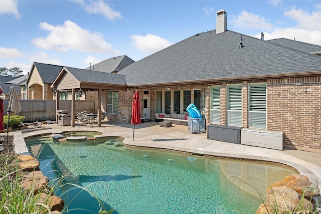 view of swimming pool featuring a pool with connected hot tub, a patio area, fence, and grilling area