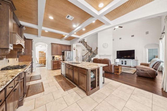 kitchen featuring arched walkways, appliances with stainless steel finishes, open floor plan, and a sink