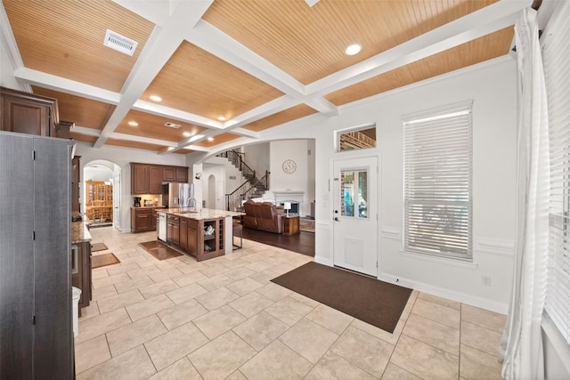 kitchen featuring arched walkways, coffered ceiling, stainless steel fridge, and wood ceiling