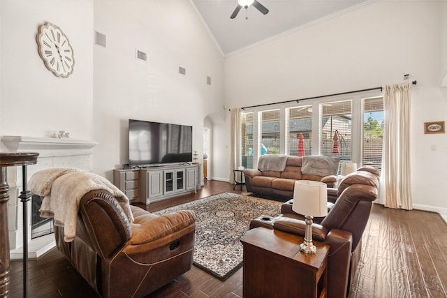 living room featuring a healthy amount of sunlight, baseboards, arched walkways, and dark wood-style flooring