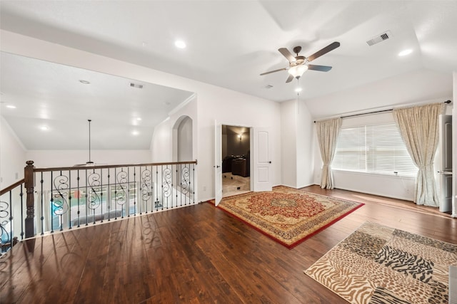 empty room featuring a ceiling fan, wood-type flooring, visible vents, and vaulted ceiling