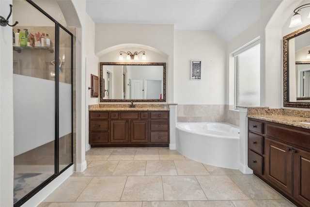 full bathroom with two vanities, a sink, a shower stall, and a bath