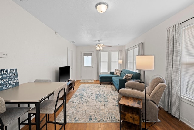 living room featuring ceiling fan, baseboards, and wood finished floors