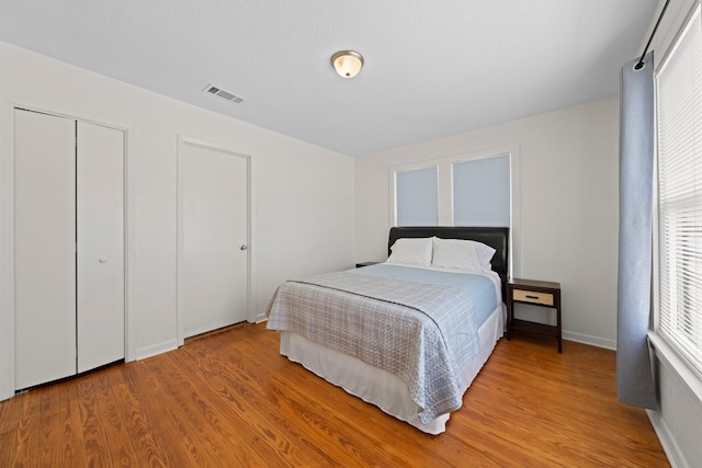 bedroom featuring light wood-type flooring, baseboards, and visible vents