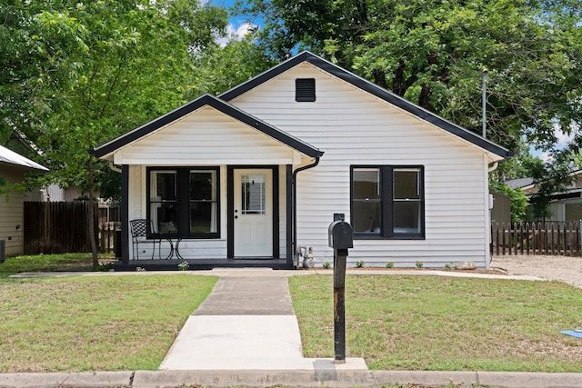 bungalow-style house with covered porch, a front yard, and fence