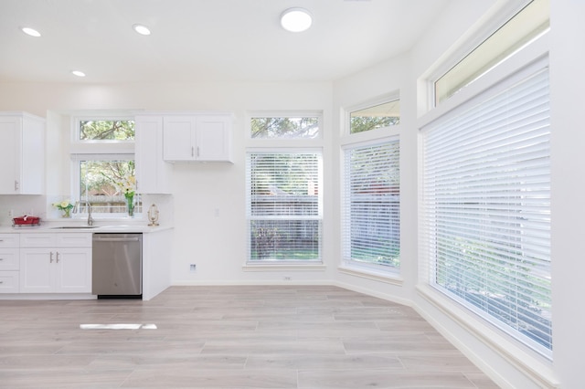 kitchen featuring a wealth of natural light, white cabinets, dishwasher, and light countertops