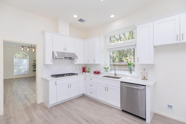 kitchen with visible vents, dishwasher, stovetop, under cabinet range hood, and a sink