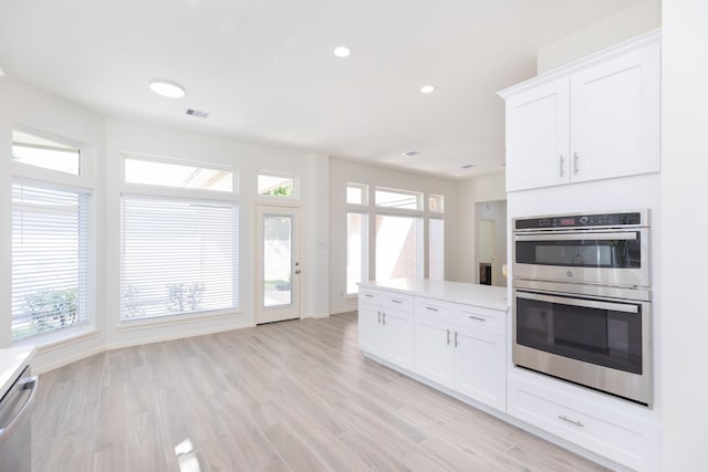 kitchen featuring stainless steel appliances, visible vents, white cabinets, light countertops, and light wood finished floors