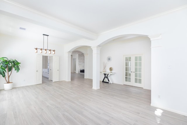 spare room featuring light wood finished floors, baseboards, visible vents, and crown molding