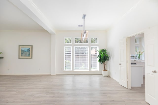 unfurnished dining area featuring light wood finished floors, visible vents, ornamental molding, and baseboards