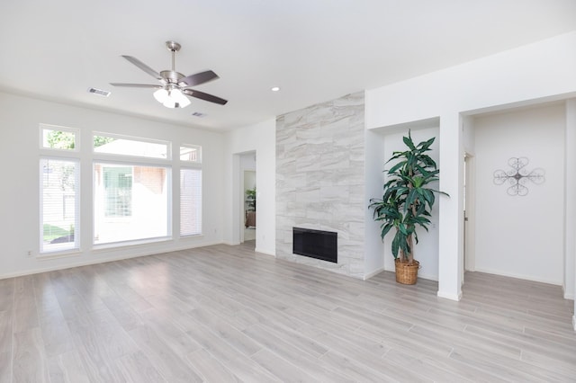 unfurnished living room featuring light wood-type flooring, ceiling fan, visible vents, and a tiled fireplace