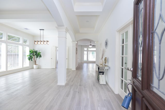 foyer with arched walkways, light wood-style flooring, a ceiling fan, ornate columns, and crown molding