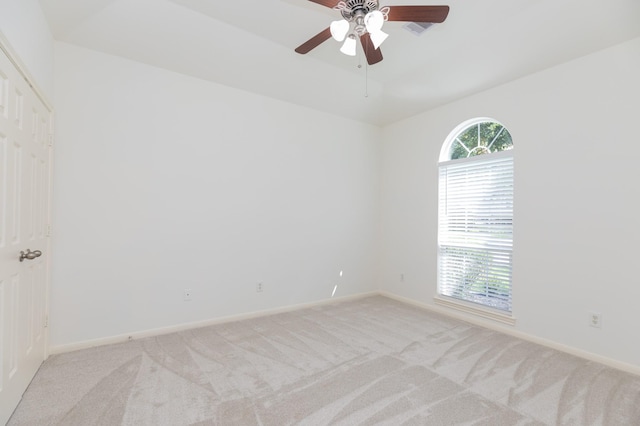 spare room featuring light carpet, ceiling fan, and baseboards