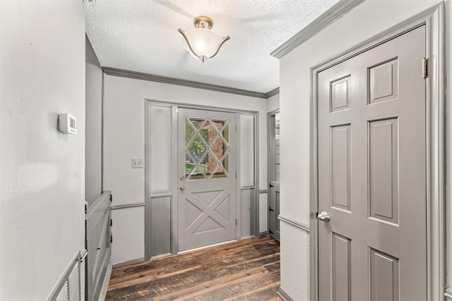 entryway featuring ornamental molding, dark wood finished floors, and a textured ceiling