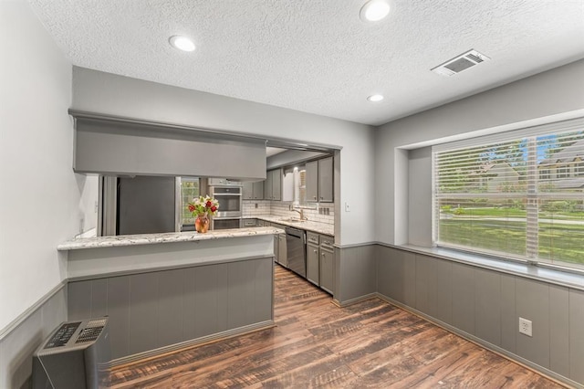 kitchen featuring visible vents, a wainscoted wall, appliances with stainless steel finishes, dark wood-style flooring, and gray cabinetry