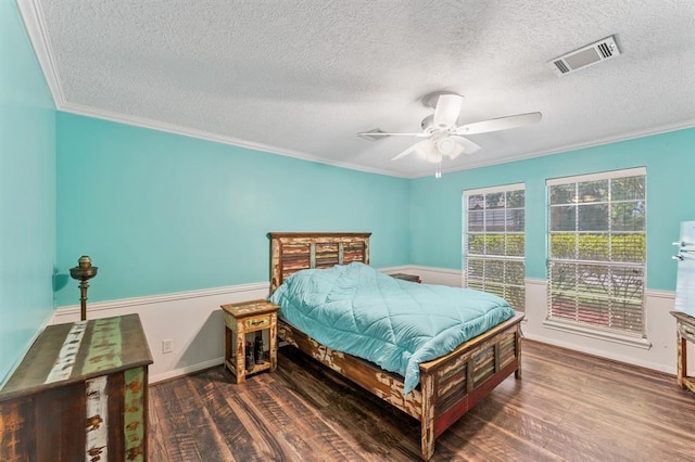 bedroom featuring visible vents, a ceiling fan, ornamental molding, wood finished floors, and a textured ceiling