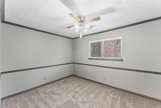 spare room featuring carpet, ornamental molding, ceiling fan, a textured ceiling, and baseboards