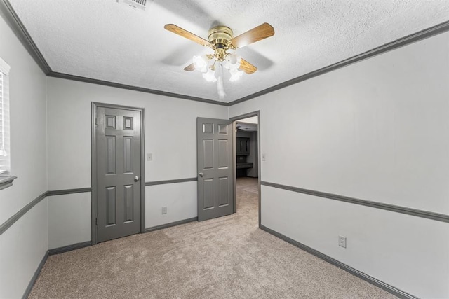 carpeted empty room with crown molding, baseboards, ceiling fan, and a textured ceiling