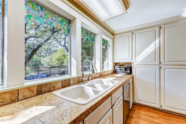 kitchen with tile countertops, light wood-style flooring, white cabinets, and a sink