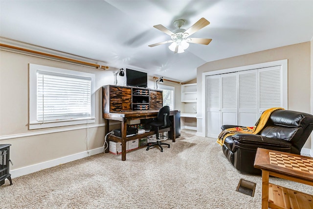 carpeted office space featuring vaulted ceiling, a ceiling fan, and baseboards