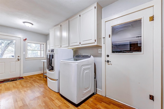 clothes washing area featuring cabinet space, light wood-style flooring, baseboards, and washing machine and clothes dryer