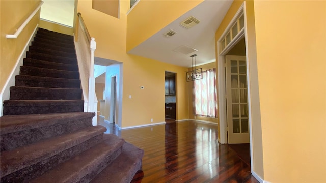 interior space with stairs, visible vents, baseboards, and wood finished floors