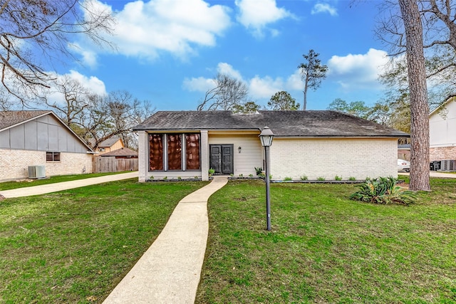 mid-century home featuring central AC unit, brick siding, a front yard, and fence