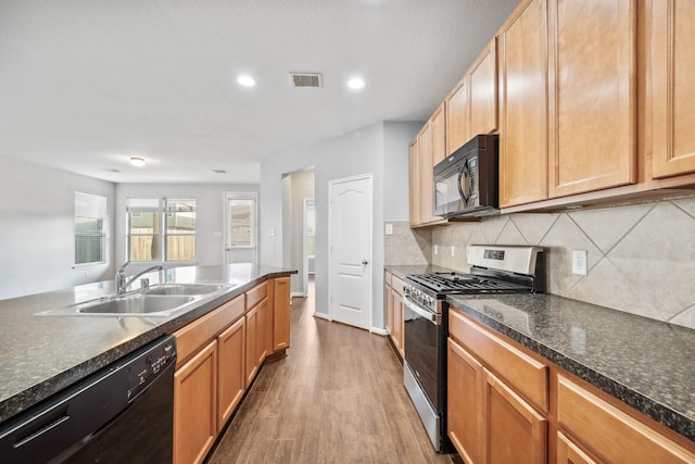 kitchen featuring dark wood finished floors, tasteful backsplash, visible vents, a sink, and black appliances